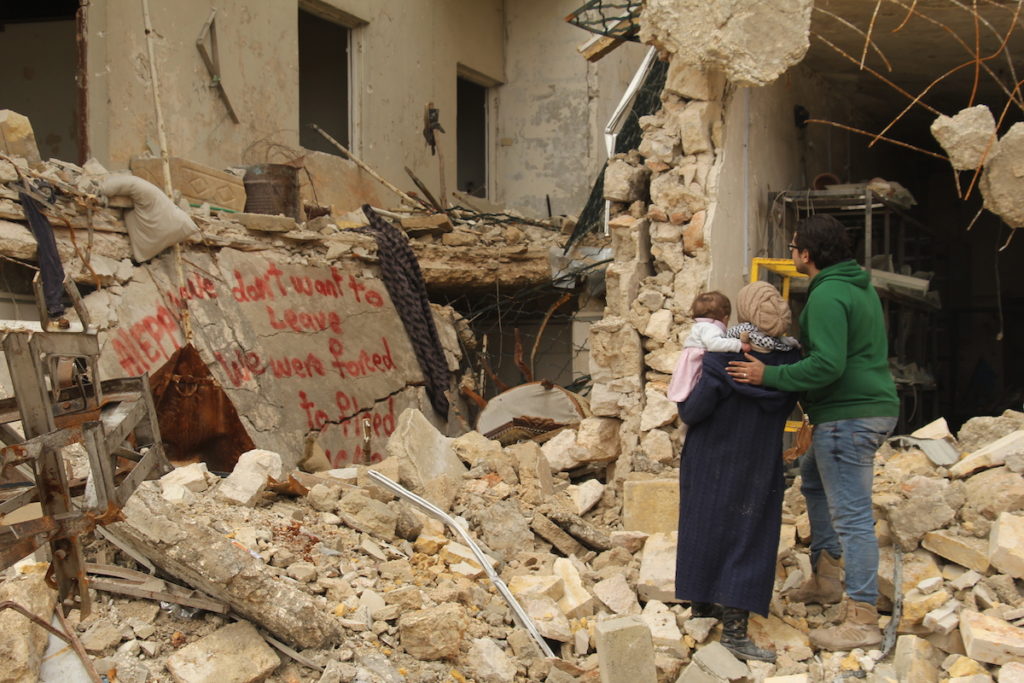 FOR SAMA.  Waad, Hamza and Sama look at graffiti they painted on a bombed-out building, protesting against the forced exile of the civilian population of east Aleppo by forces of the Syrian regime and their Russian and Iranian allies, December 2016. Courtesy of Channel 4, Copyright Waad al-Kateab.