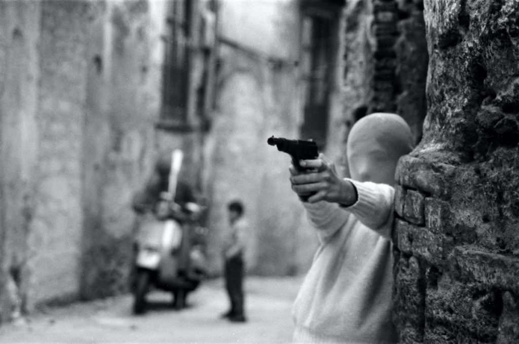 Film subject Letizia Battaglia’s photo Palermo, 1982. Vicino alla Chiesa di Santa Chiara. Il gioco del killer. (“Palermo, 1982. Near the Church of Santa Chiara. The game of the killer.”) in Shooting the Mafia, directed by Kim Longinotto . Courtesy of Cohen Media Group.